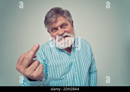 Funny senior man posing in a  photoshooting. Happy hipster doing funny expressions. Concept about people and lifestyle. Stock Photo