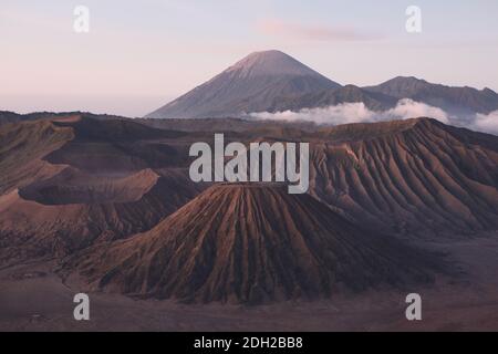 Mount Semeru and the group of volcanoes on the bottom of the Tengger Caldera in East Java, Indonesia, pictured from Mount Penanjakan (2,770 m) at the edge of the Tengger Caldera. Mount Batok (2,470 m) is seen in the foreground; Mount Bromo (2,329 m) is a volcano behind at the left; Mount Kursi (2,581 m) is directly behind Mount Batok; Mount Semeru (3,676 m), the highest point in Java, is seen in the background. Stock Photo