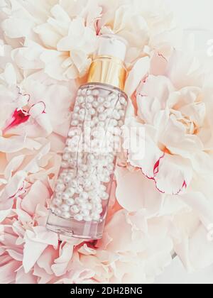 Luxurious cosmetic bottle as antiaging skincare product on background of flowers, blank label packaging for body care branding Stock Photo