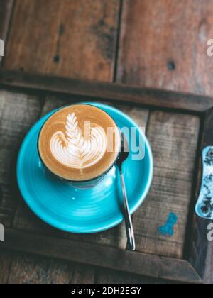 Cup of hot latte art coffee on vintage wooden table. Stock Photo