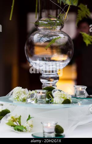 Holders with burning candles and decoration on table against blurred background. Stock Photo