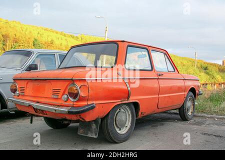 Bright red soviet retro car ZAZ or Zaporozhets. Old red rusty and dirty retro automobile back view. Stock Photo