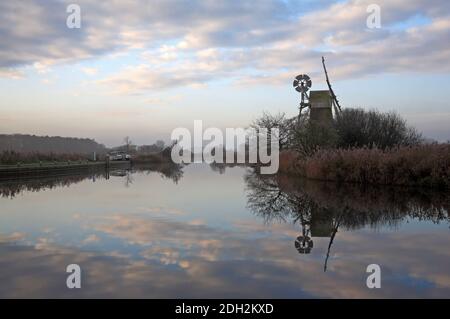 A view of the River Ant on a misty winter morning passing Turf Fen Drainage Mill on the Norfolk Broads at Ludham, Norfolk, England, United Kingdom. Stock Photo
