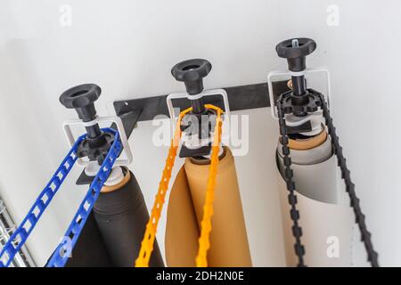 mounting manual support system for photo backdrops in modern studio. Rolls of colorful paper backgrounds for photo studio hang on the wall Stock Photo