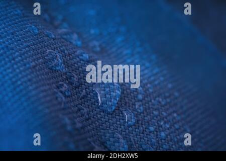 Water drops on waterproof impregnated blue fabric. Stock Photo
