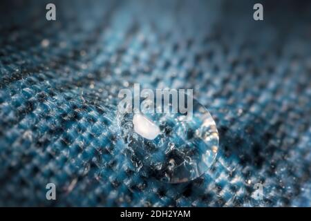 Close-up view on water drop on blue waterproof fabric. Stock Photo