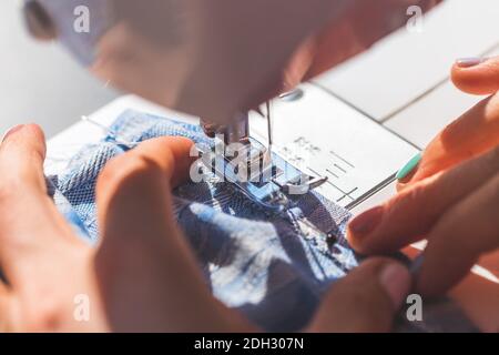 Sewing at home: Woman is sewing at home, close up of sewing needle, textile and hands Stock Photo