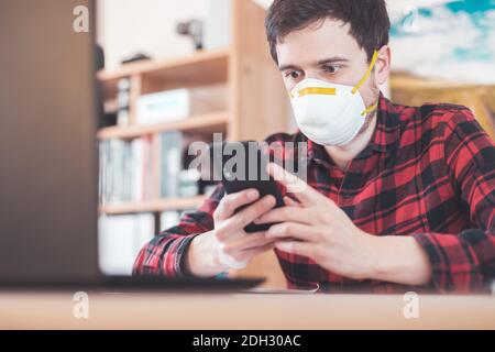 Protection in office in corona crisis: Man with face mask is sitting on his workplace Stock Photo