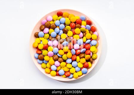 Multicolored Chocolate candy in plate on white background. Top view Stock Photo