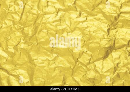 Illuminating golden paper texture. Wrinkled foil background. Color of the year 2021. Stock Photo