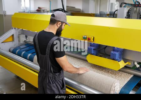 Man operating carpet automatic washing machine in professional laundry service Stock Photo