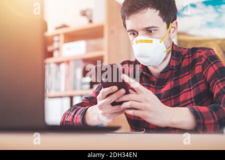 Protection in office in corona crisis: Man with face mask is sitting on his workplace Stock Photo