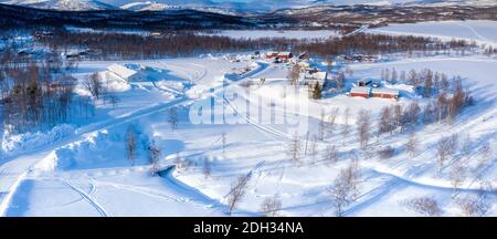 Scenic aerial view on small Tarna Vilt village in Swedish Lapland in winter cover, frosty sunny day. Roads, houses, frozen lakes, birch trees with Sca Stock Photo