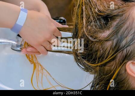 Hairdresser washing hair of woman client at beauty salon - close up view Stock Photo