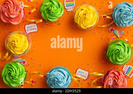 Colorful cupcakes arranged on an orange background for a festive birthday celebration Stock Photo