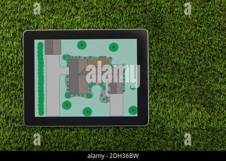 Landscape design plan displayed on tablet on green grass surface in a residential area Stock Photo