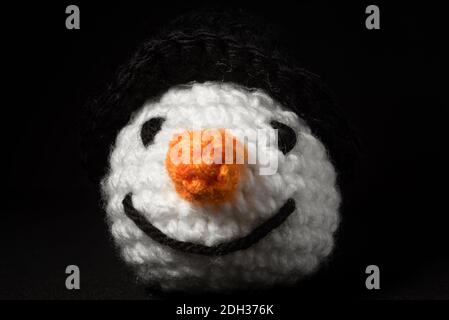 Portrait of Amigurumi Snowman crocheted or knitted stuffed toy on black background Stock Photo