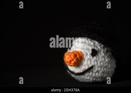 Portrait of Amigurumi Snowman crocheted or knitted stuffed toy on black background Stock Photo