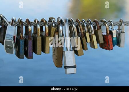 Old rusty metal padlocks hanging on string above river Stock Photo
