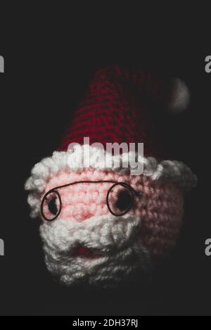 Portrait of Santa Claus Amigurumi crocheted or knitted stuffed toy on black background Stock Photo