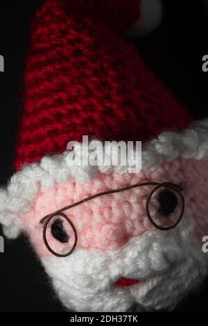Portrait of Santa Claus Amigurumi crocheted or knitted stuffed toy on black background Stock Photo