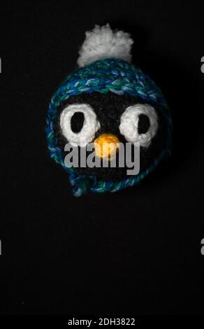 Portrait of Christmas Amigurumi penguin crocheted or knitted stuffed toy on black background Stock Photo