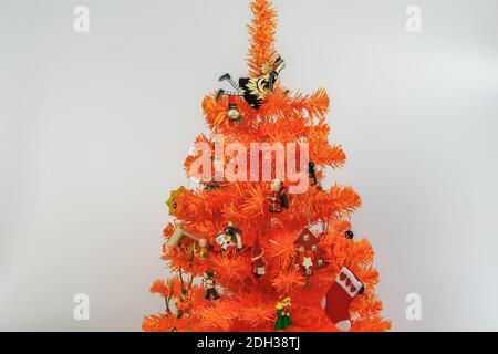 Artificial orange Christmas tree with ornaments against white background. Wooden miniature festive decorations hanging on  branches of orange tree. Stock Photo
