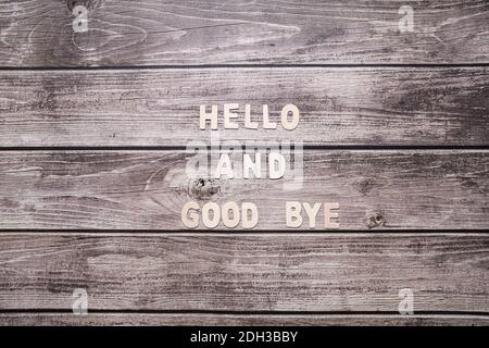 Hello and good bye wooden letters written no a striped wooden background Stock Photo