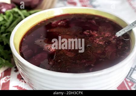 Ukrainian borscht in a ceramic plate on the kitchen table. Stock Photo