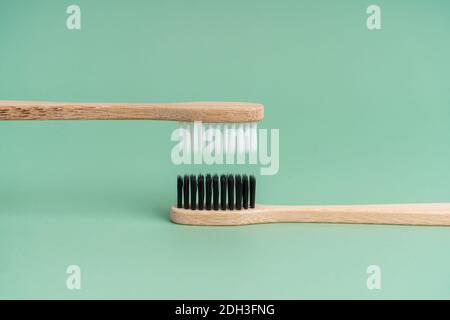 Two Eco-friendly antibacterial bamboo wood toothbrushes with white and black bristles on a light green background. Taking care of the environment is t Stock Photo