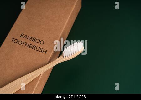 Eco-friendly antibacterial bamboo wood toothbrush on dark green background. Taking care of the environment in trend. Stock Photo