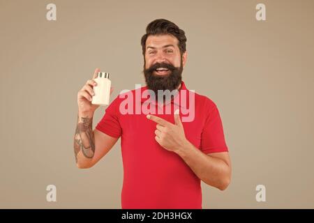 Side effects. Medicines concept. Food additives vitamins for male health. Vitamin complex. Handsome bearded man take medication. Health care. Hipster hold plastic container. Investment in health. Stock Photo