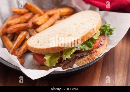 home made roast beef sandwich on sourdough bread with crispy french fries Stock Photo