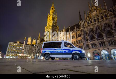 Munich, Germany. 09th Dec, 2020. A police car drives across the deserted Marienplatz in the centre of the city. In the background you can see the decorated Christmas tree in front of the town hall and the two spires of the Frauenkirche (left). From Wednesday (09.12.2020) there is a curfew between 21.00 and 5.00 hours in the Bavarian capital. Credit: Peter Kneffel/dpa/Alamy Live News Stock Photo