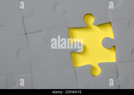 Multiple grey puzzle pieces put together without one piece on yellow background. Colors of year 2021. Place for text. Stock Photo