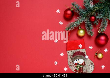 Christmas composition of fir tree branches, baubles, Christmas stocking and snowflakes on red background with copy space for text. Christmas and New Y Stock Photo
