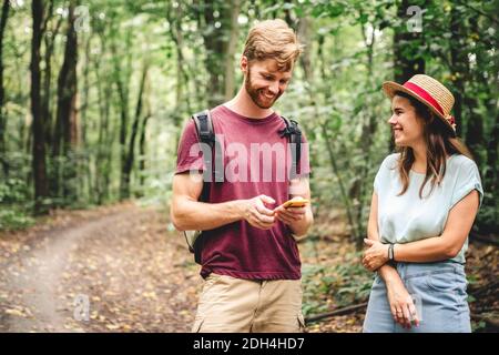 Hikers using mobile gps for directions. Happy couple checking smartphone in the woods during backpacking trip. Young joyful coup Stock Photo