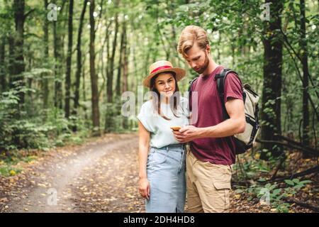 Couple using smart phone to navigate in woods. Theme tourism and navigation, search way, create route, gps phone app. Two people Stock Photo