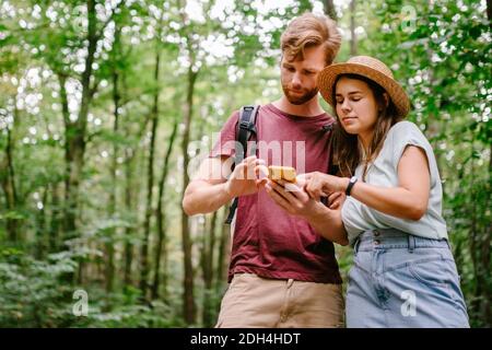 Hikers using mobile gps for directions. Happy couple checking smartphone in the woods during backpacking trip. Young joyful coup Stock Photo