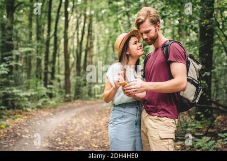 Couple hiking and using maps app on cell phone. Two people hikers looking at mobile phone trying find route. Hike in forest, loo Stock Photo