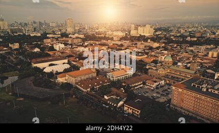 Sun shine over city roofs at green park aerial. Urban nature landscape at sunlight. Metropolis town cityscape with modern buildings at street. Philippines capital Manila Stock Photo