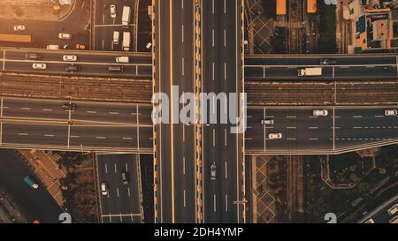 Sun at top down traffic cross road aerial. Urban transportation with cars, trucks, buses at sunlight. Amazing scenery of metropolis cityscape of Manila, Philippines, Asia Stock Photo