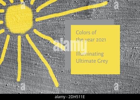 Background grey smooth concrete wall with painted yellow sun. Colors of year 2021. Stock Photo