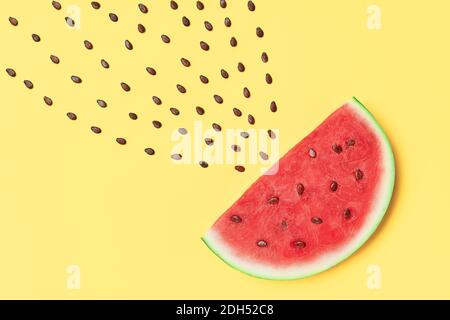 Watermelon slice with seeds on yellow background. food art Stock Photo