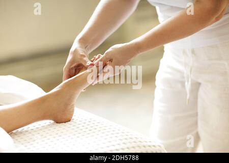 Crop masseuse making feet massage to client Stock Photo
