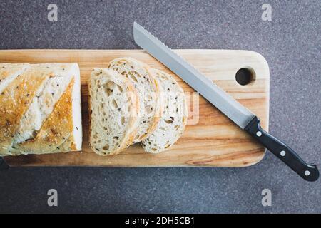 simple food ingredients concept, sourdough bread with mixed seeds sliced up on cutting board next to bread knife Stock Photo