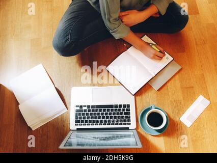 Crop designer using laptop on floor Stock Photo