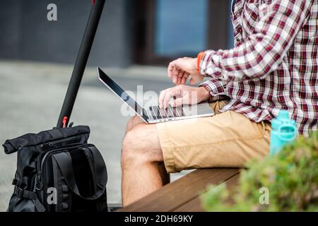 Man is using touchpad and keypad of notebook, close-up of hands. Male hands on keyboard, concept of businessman, working outdoor Stock Photo