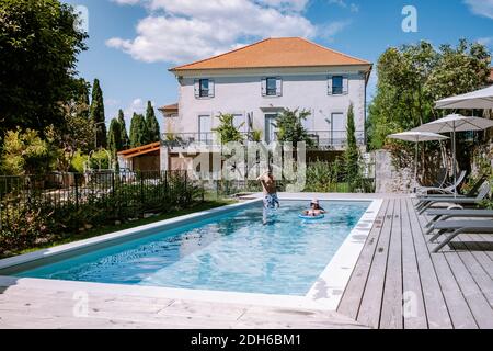 French vacation home with wooden deck and swimming pool in the Ardeche France. Couple relaxing by the pool with wooden deck duri