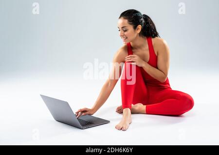 Girl makes yoga exercise online with laptop on the white background Stock Photo